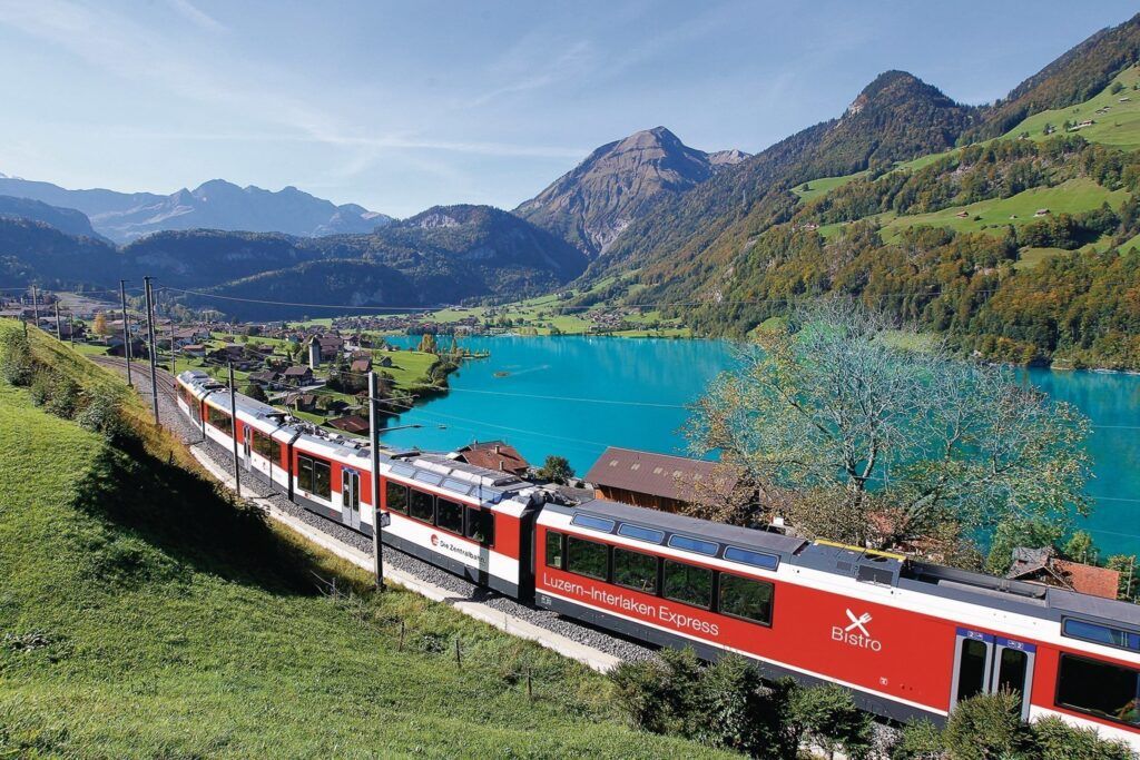 A train moving alongside a lake in Europe.