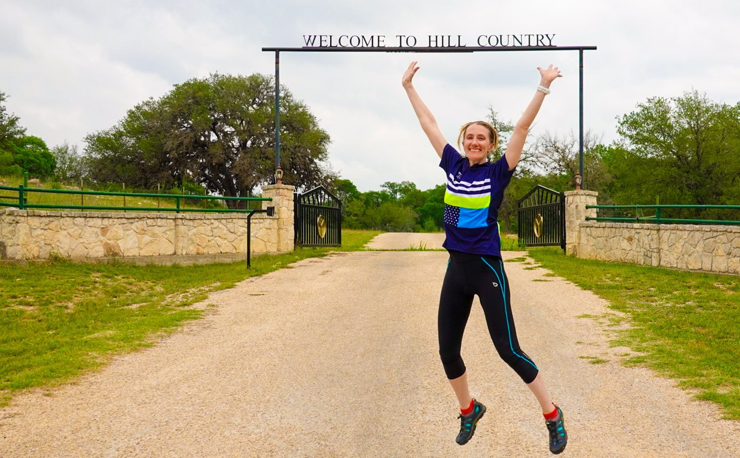 guest jumping with joy in front of the Texas Hill Contry rod iron sign in her Trek Travel jersey