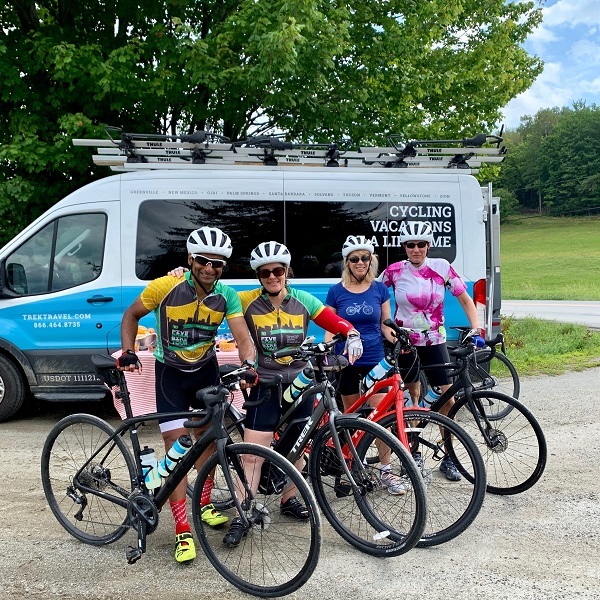 four cyclists standing in front of a van