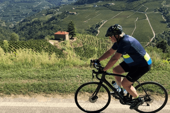 Cyclist riding with rolling hills and vineyards in the background
