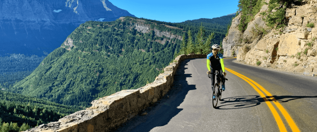 person riding their bike on a paved road over-looking mountain view.