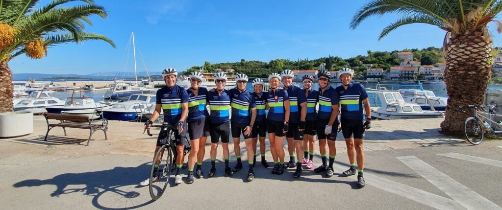 A group of people in bike jerseys standing in front of an ocean