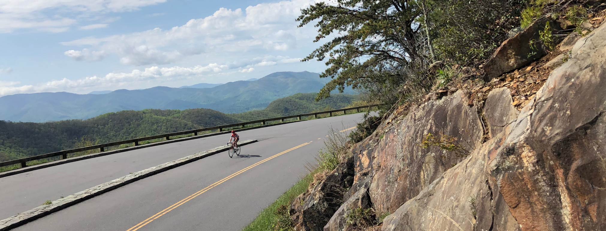person cycling on a paved road through North Carolina with a mountain view