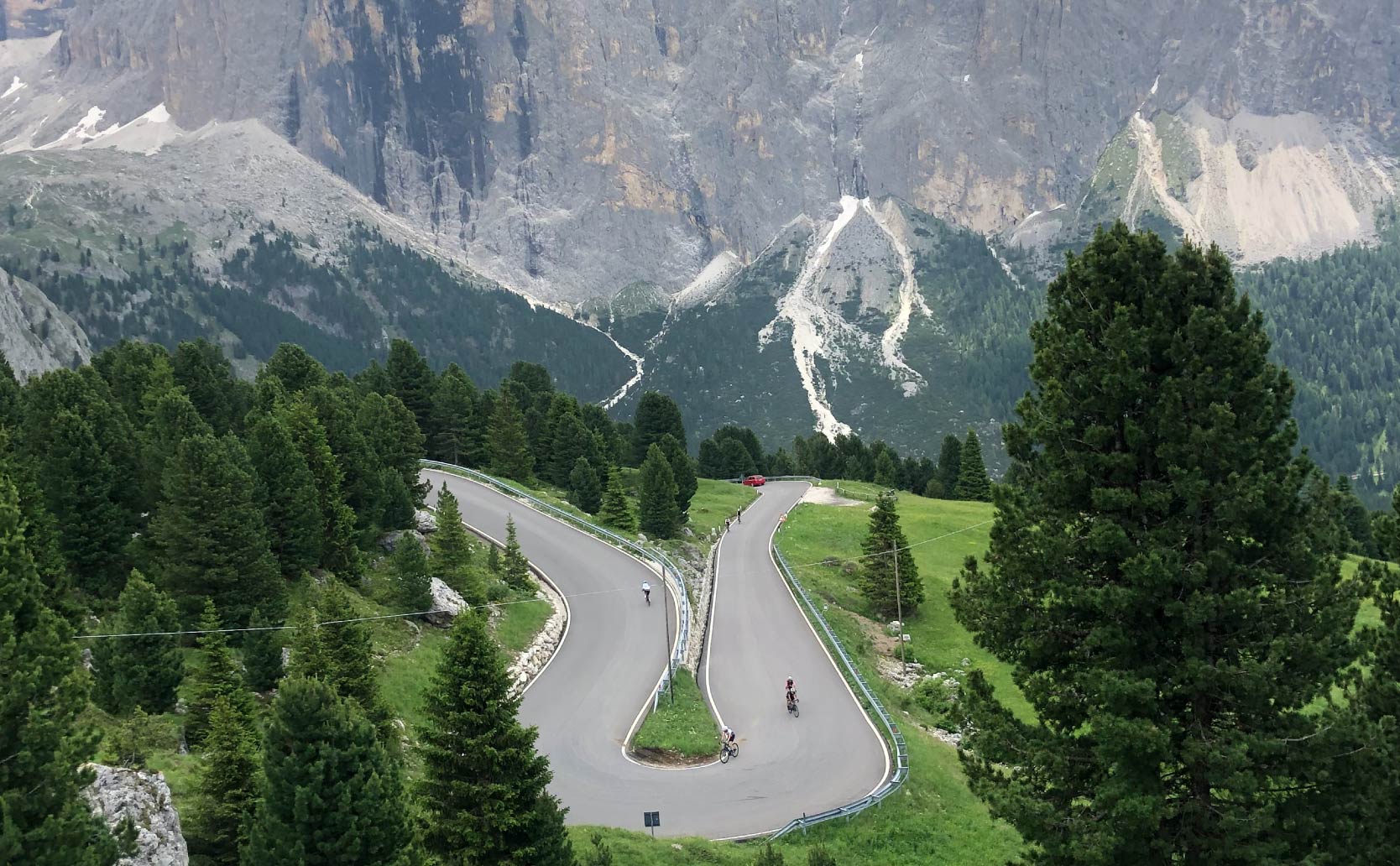 flyover view of people riding their bike on a paved road in the Dolomites