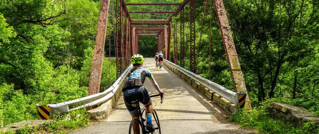 Three cyclists ride across iron bridge
