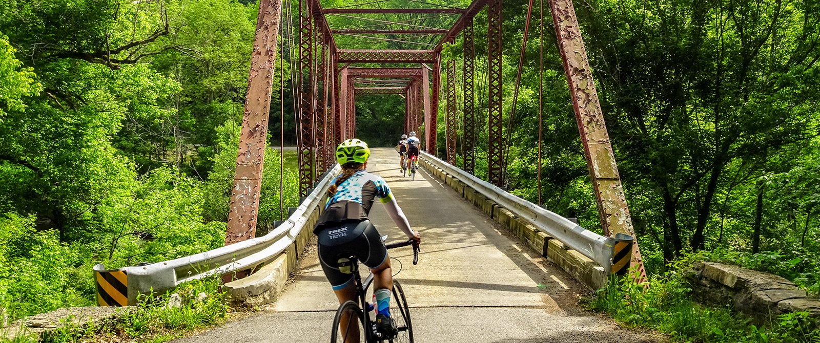 Three cyclists ride across iron bridge