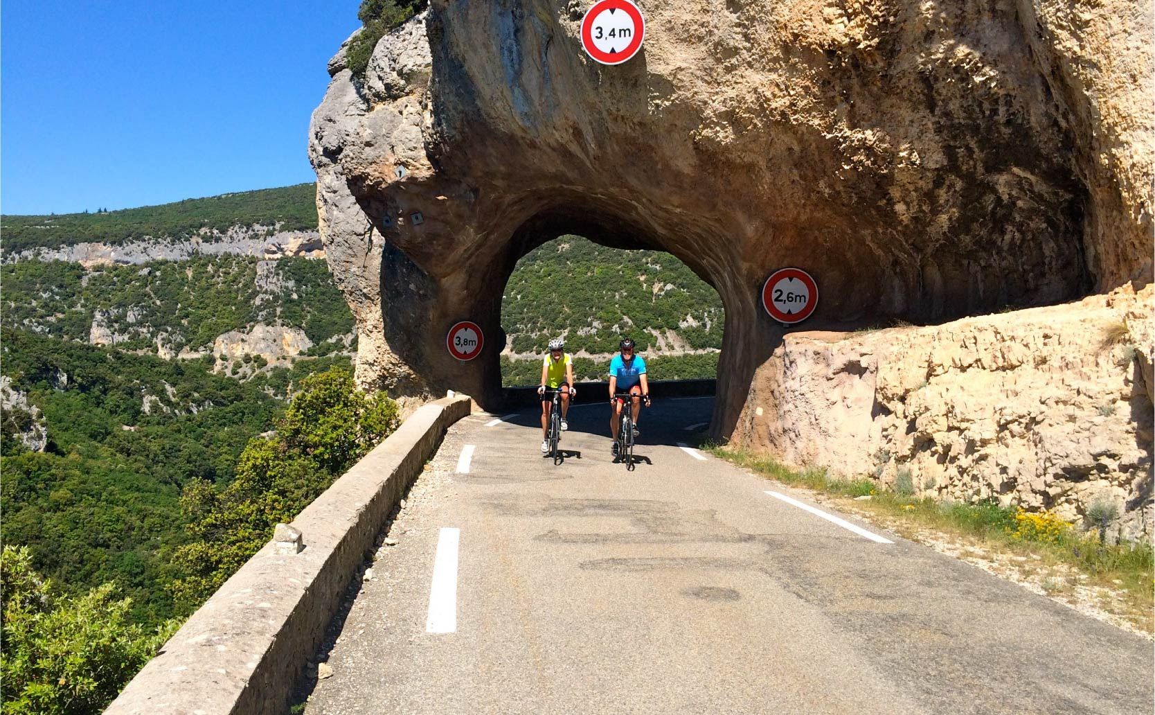 two people riding under a natural rock bridge in Gorge de la Nesque