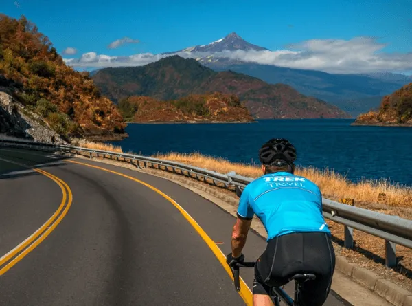 Person riding their bike through Chile on a paved road with an ocean and mountain view
