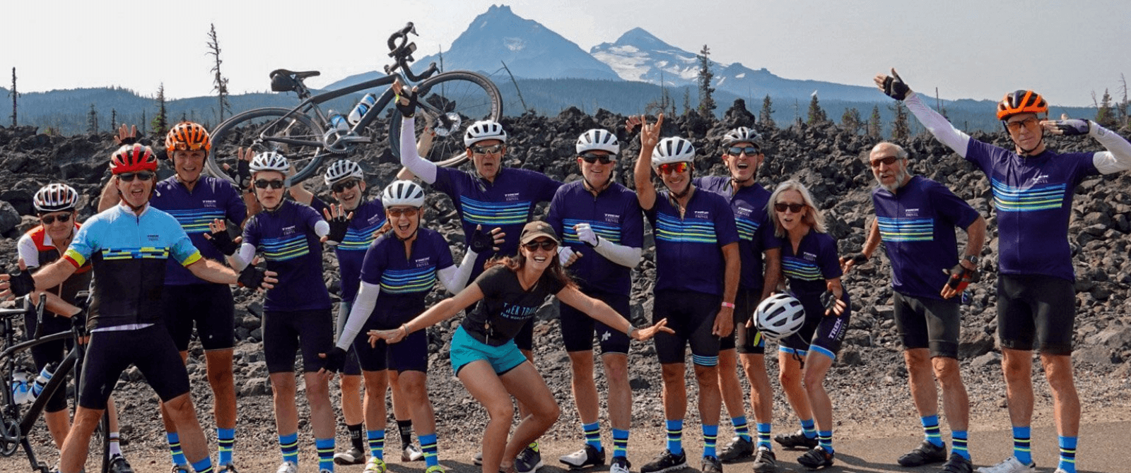 group of people posing in front of mountain view in their bike jerseys and helmets