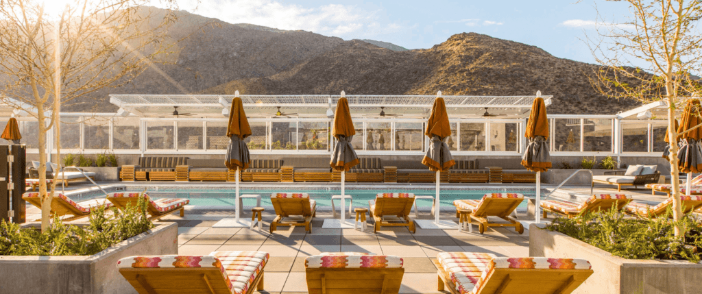 View into the sun of rooftop pool and mountains in the background