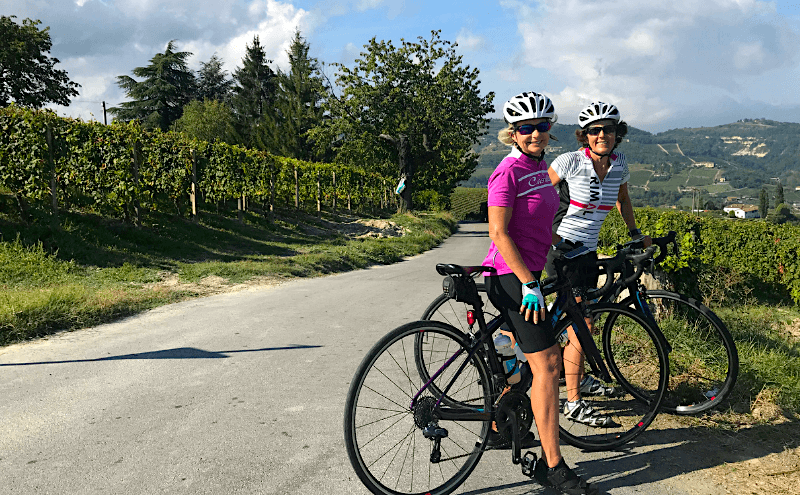 Two cyclists smile for the camera by the roadside
