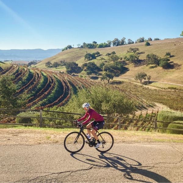 cyclist climbing a hill with california landscape in the background