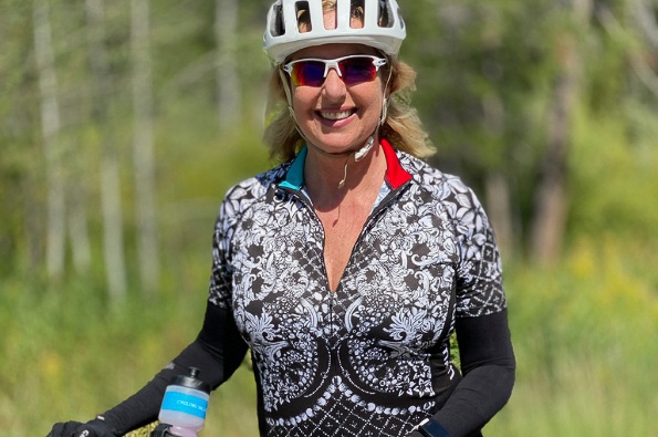 Rider smiling in front of a forested area, blurred in the background