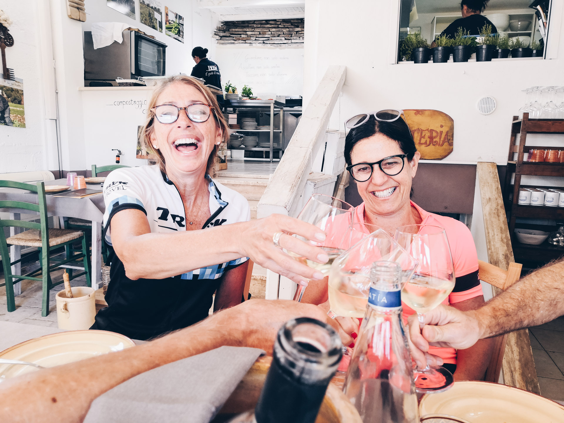 Two people laugh while making a toast in Puglia