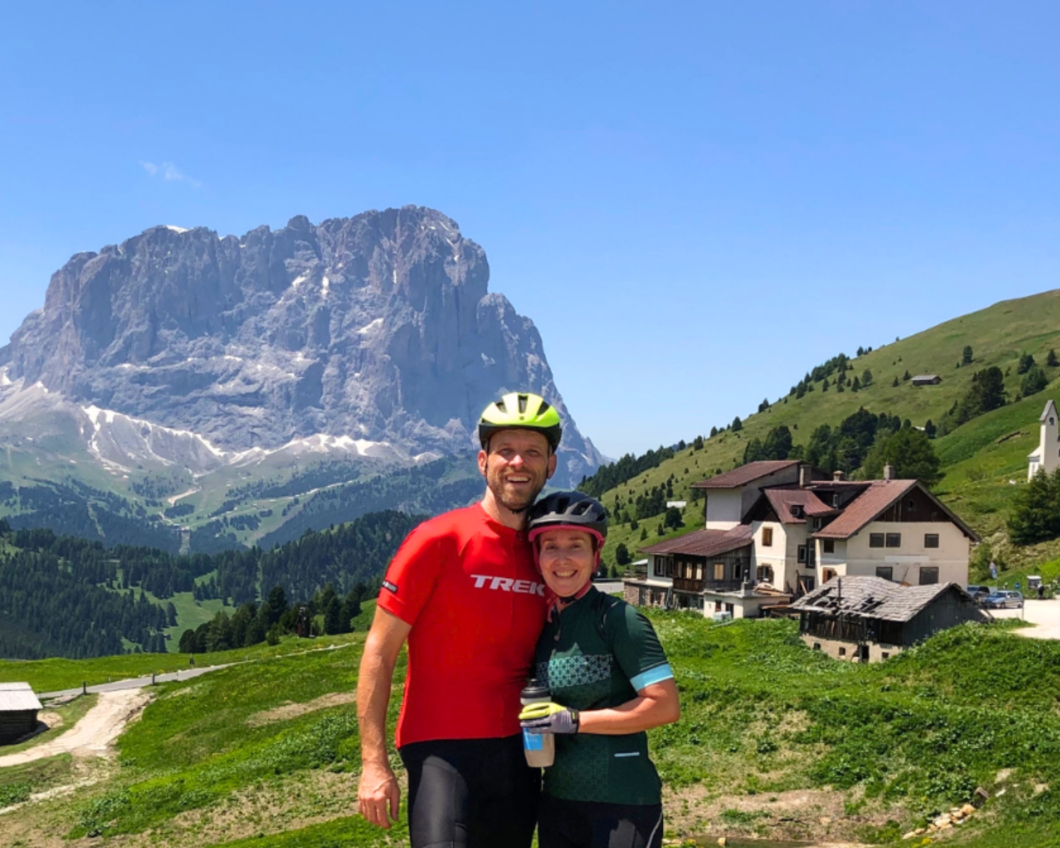 Couple embracing in front of the Dolomites Civetta mountain and alpine houses.