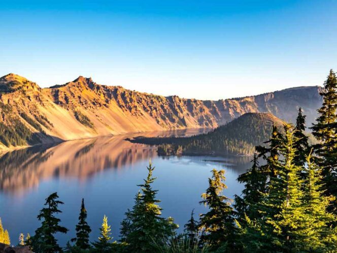 Landscape image of Crater Lake with Pine Trees in the foreground