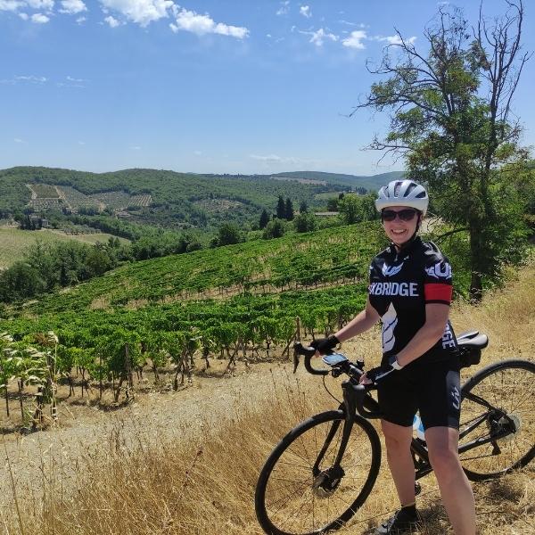 Cyclist standing in front of vineyards