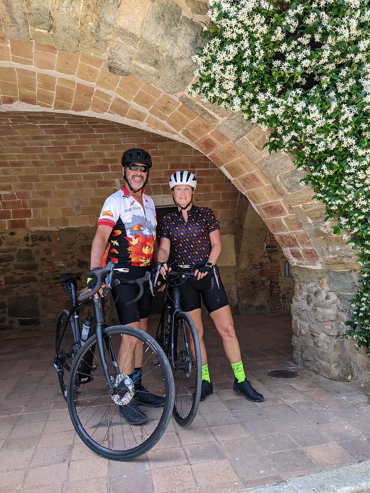 couple smiling underneath a brick cave, standing next to their bikes