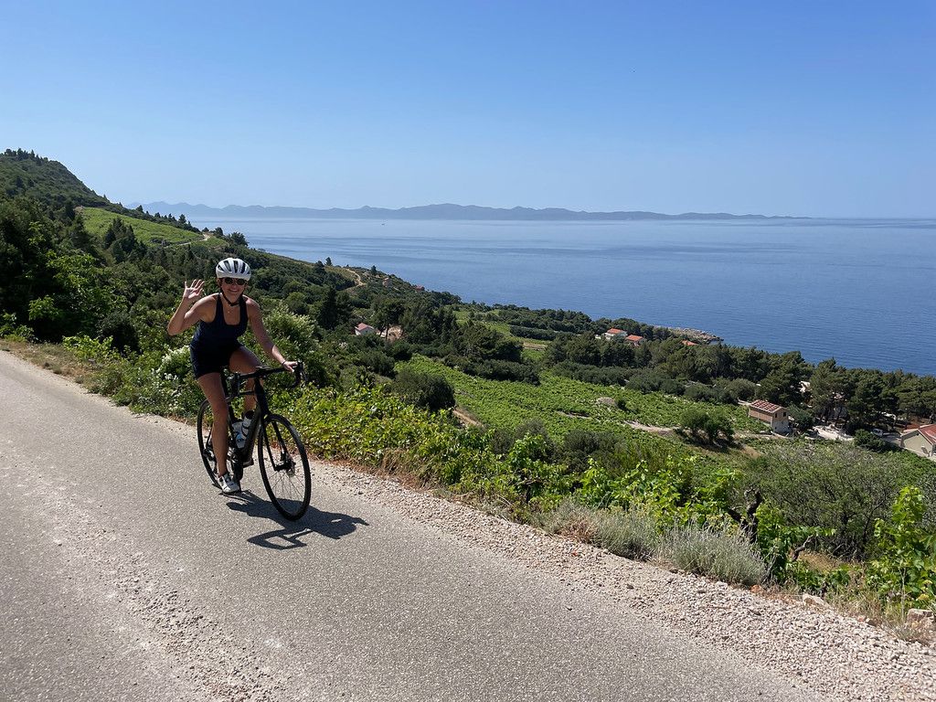 Cyclist waving with sea in the background