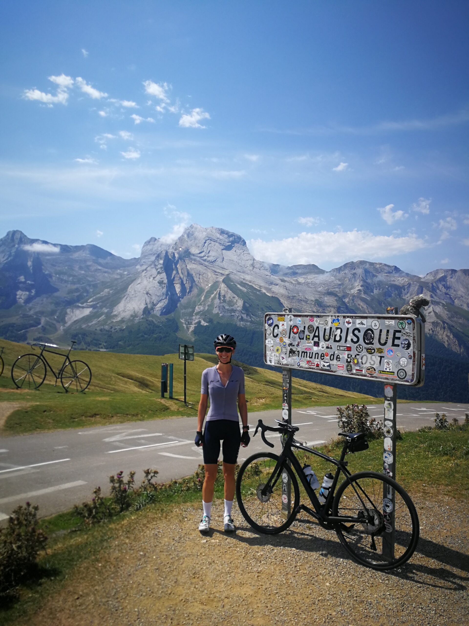 A person standing next to the Col d'Aubisque sign