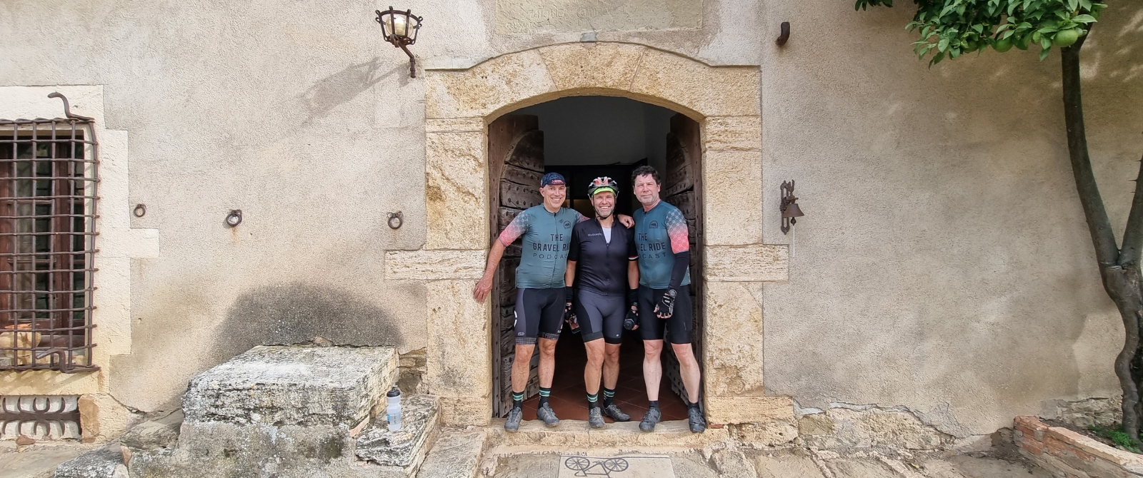 Three gravel cyclists pose in a stone door frame