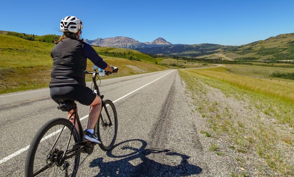 A cyclist on an ebike on an open road with rolling hills