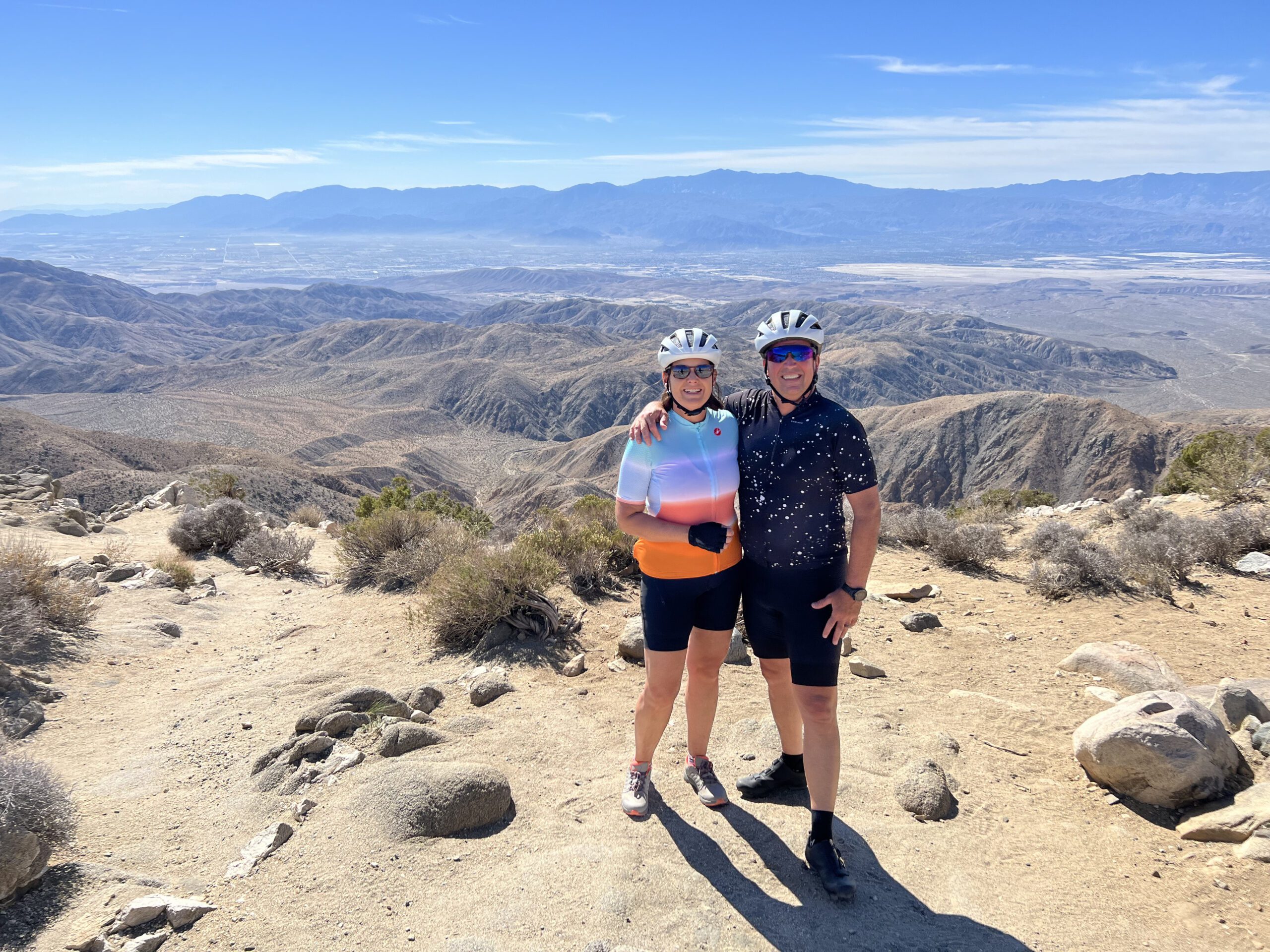 A couple pose in front of a wide vista of Joshua Tree national park