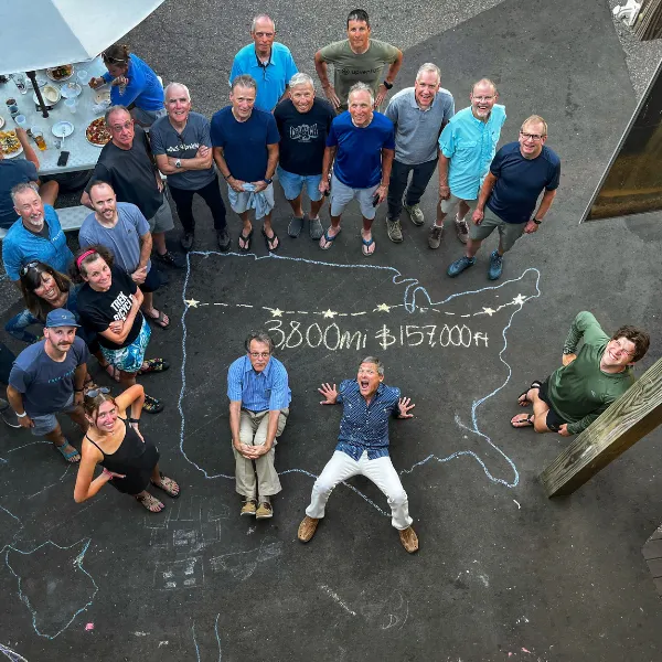 Group of people standing together smiling upwards at the camera with a chalk outline of the US on the ground beneath them