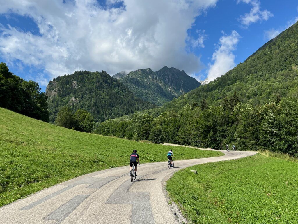 Two cyclists climb toward forested mountains