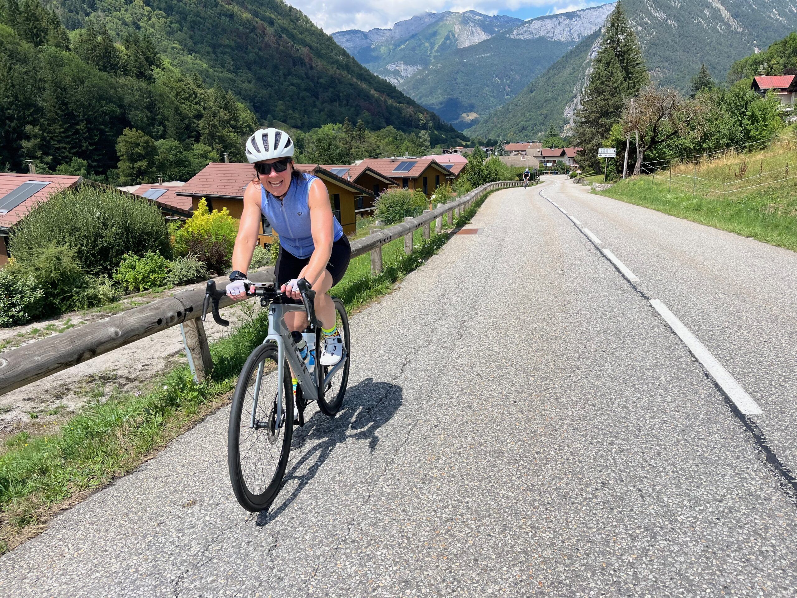 A smiling cyclist climbs a road in the mountains