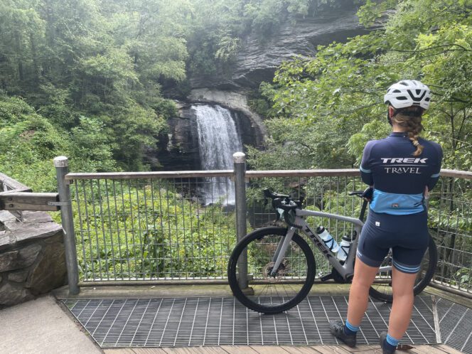 A cyclist looks at a waterfall from a look out point