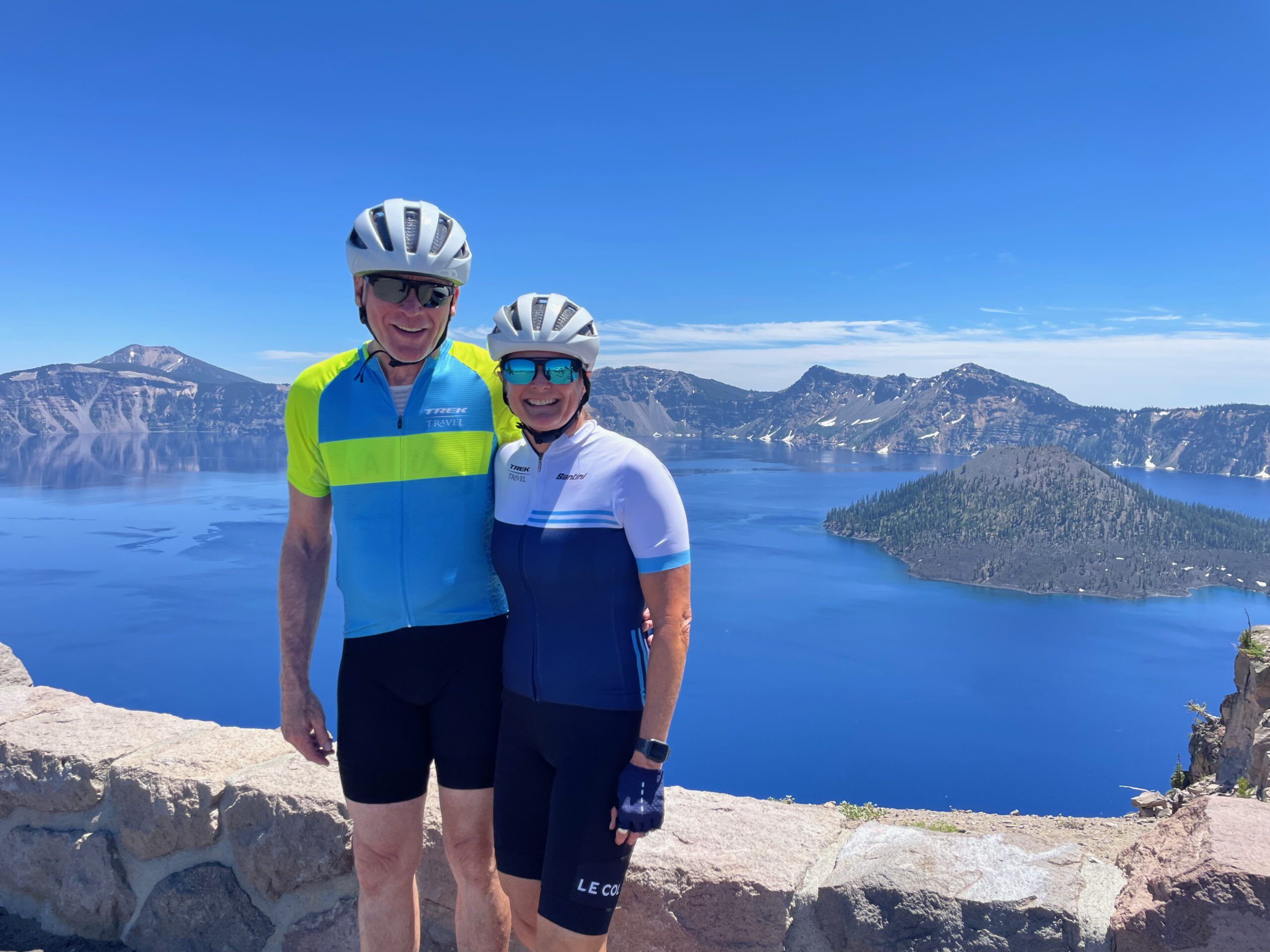 A cycling couple stands in front of Crater Lake.