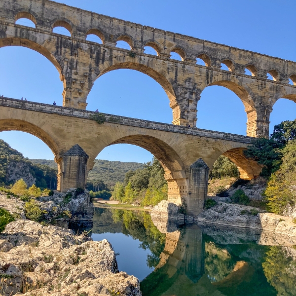 The three-tiered Roman Pont du Gard with a reflection in the river below
