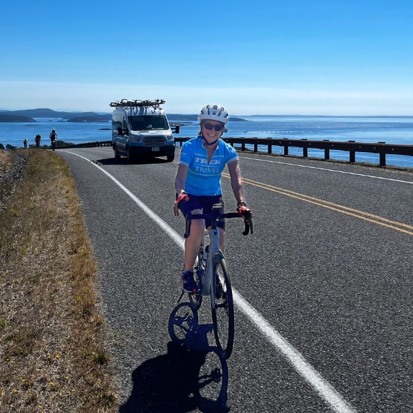 Cyclist with the Trek Travel van and ocean view in the background