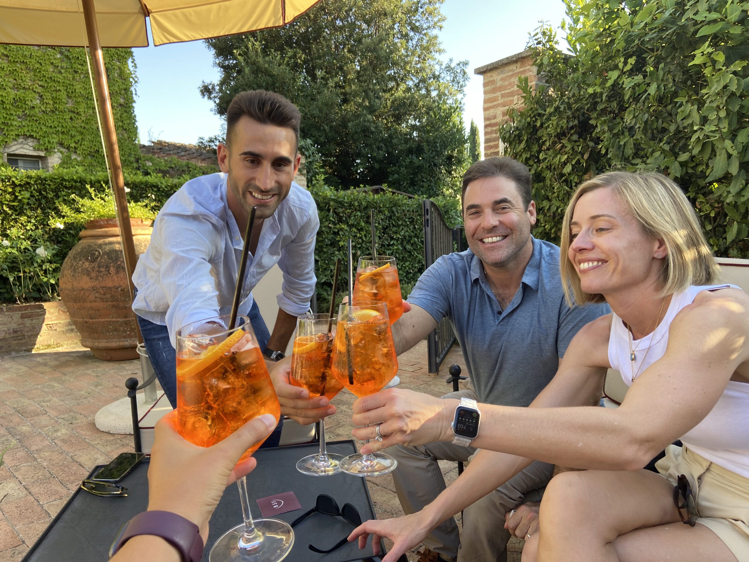 A group of people saying cheers with their Aperol Spritzes