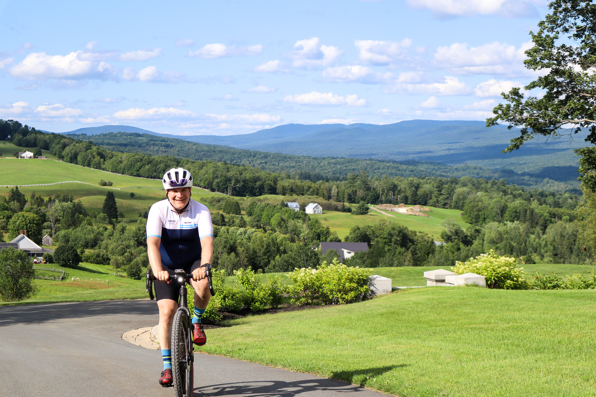 A cyclist smiling as they ride on rolling hills in Vermont