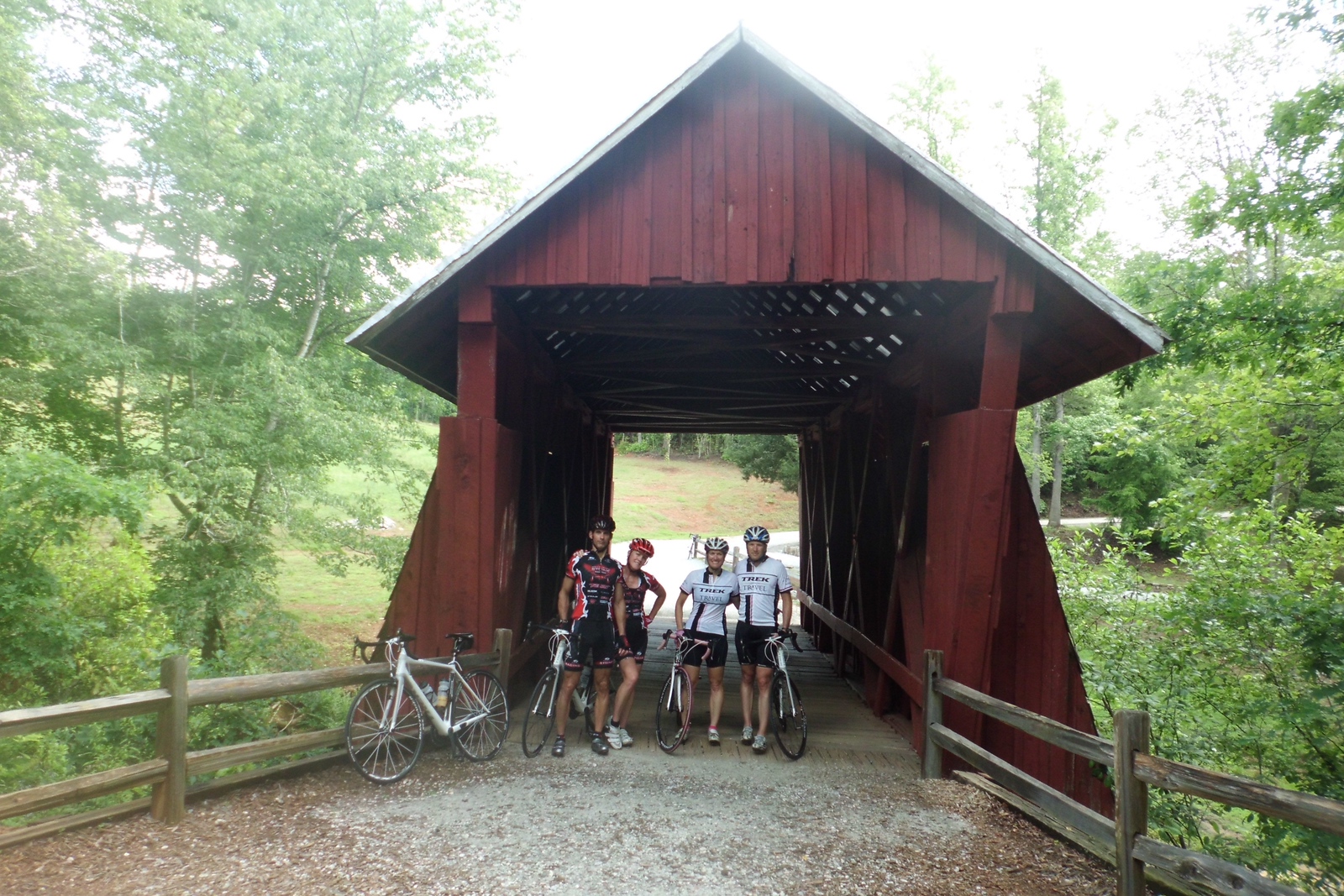 four cyclists taking a break for a photo in front of Cambell Covered bridge in Upstate South Carolina
