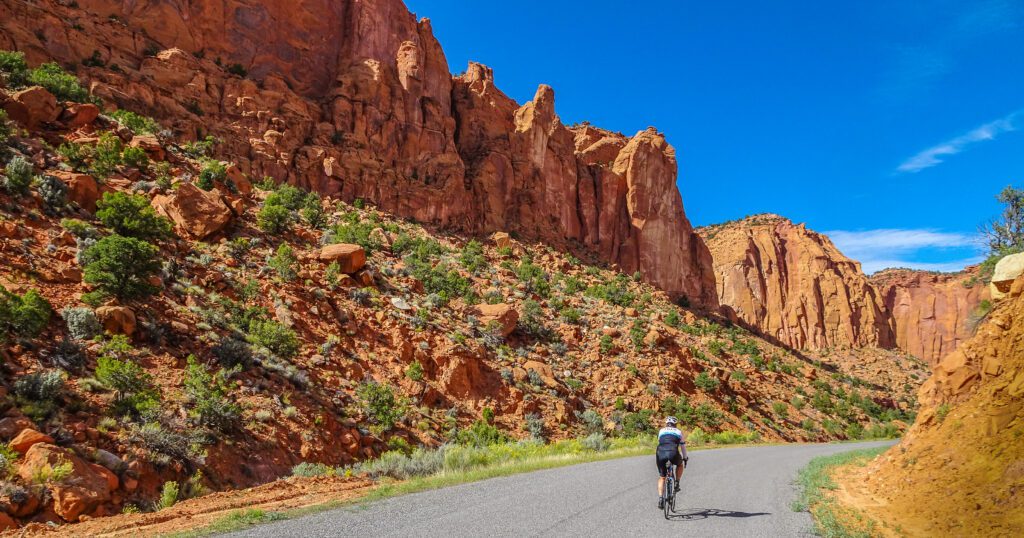 A lone cyclist rides through a red rock valley in Utah