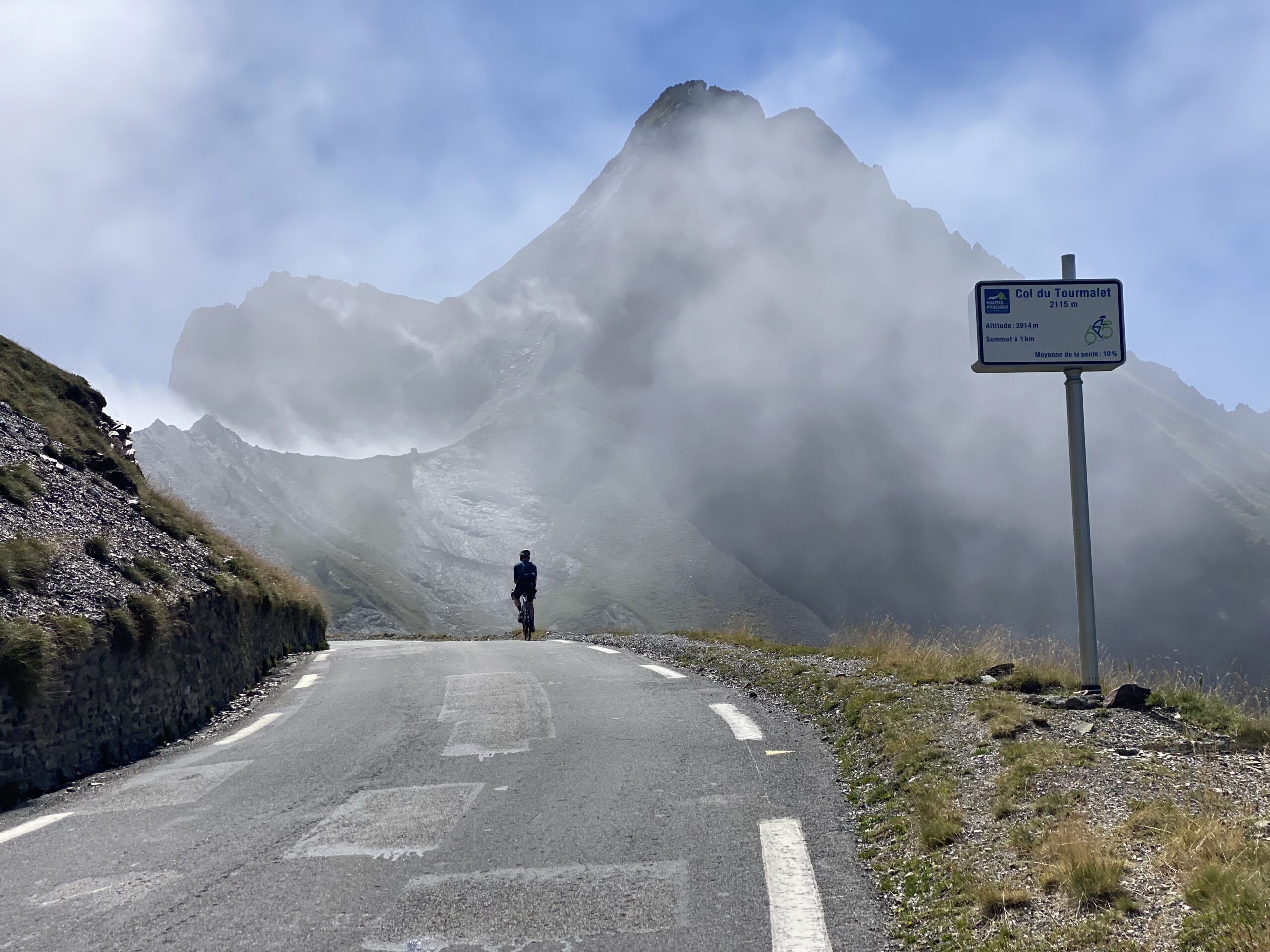 A lone cyclist rides in the mist on the summit of Col du Tourmalet