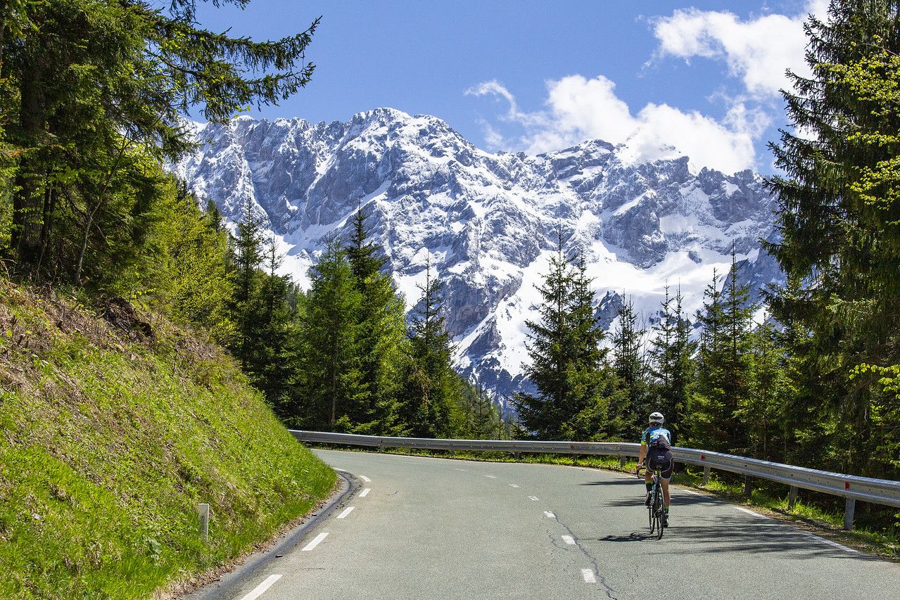 Biker riding towards snowy mountain