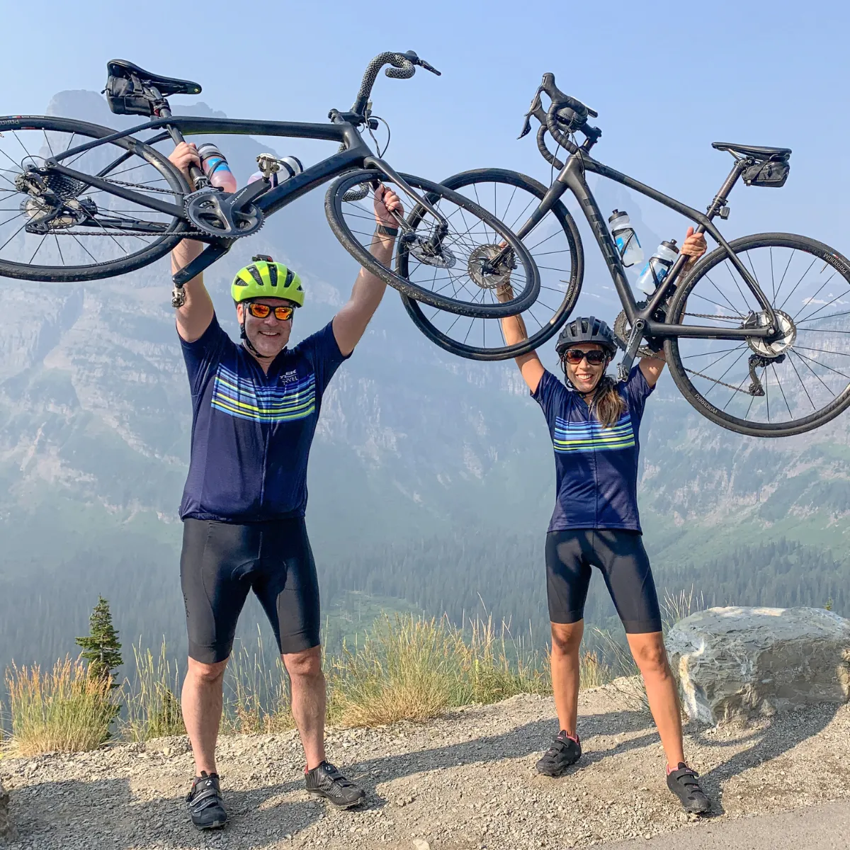 2 cyclists hoisting their bikes in Glacier National Park