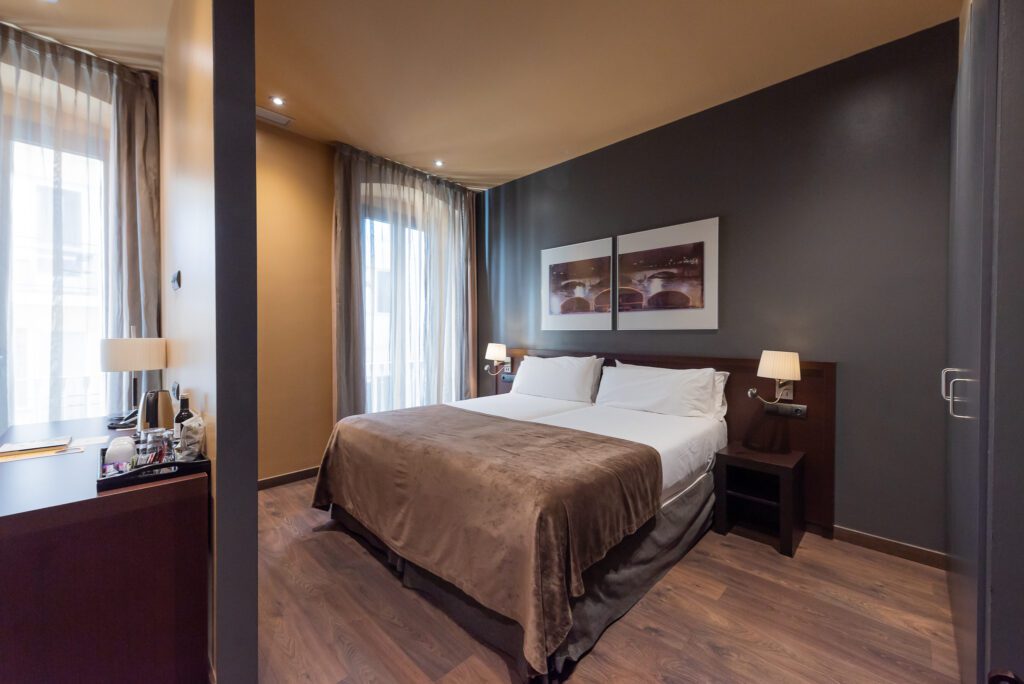 Double hotel bedroom with dark walls and wood floor