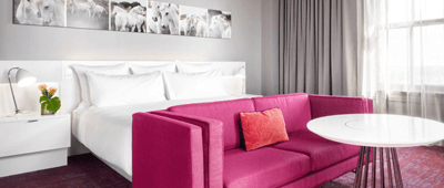 Interior view of hotel room with bed and pink couch