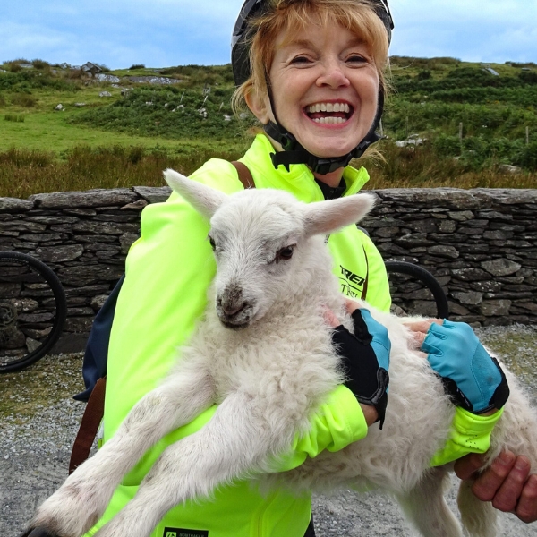 A smiling woman holding a lamb
