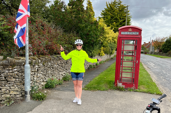 Cyclist poses beside UK telephone box and union jack