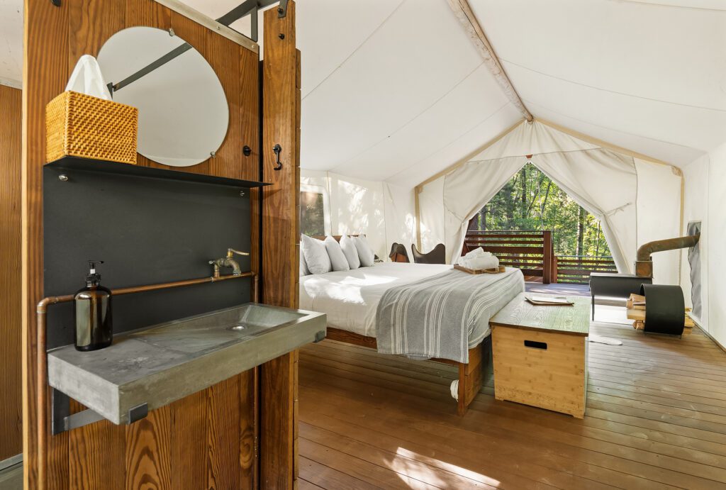 View of bathroom and bed in deluxe tent at Glacier Under Canvas
