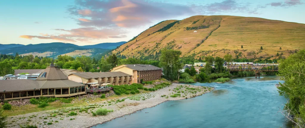 Exterior view of Doubletree in Missoula on the bank of the Clark Fork River with a mountain in the background