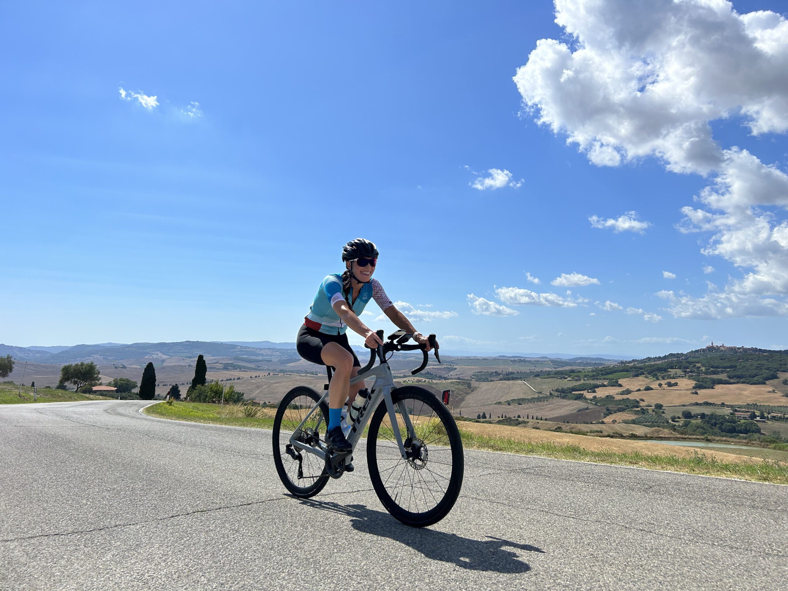 Smiling cyclist on a bright day with Tuscan landscape in the background