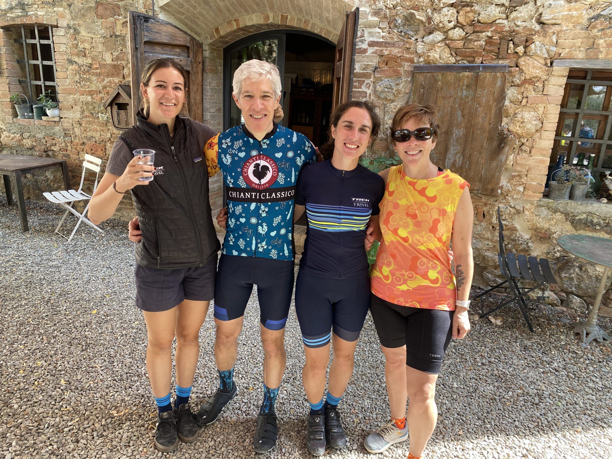 A group of four people smiling in front of an old stone building