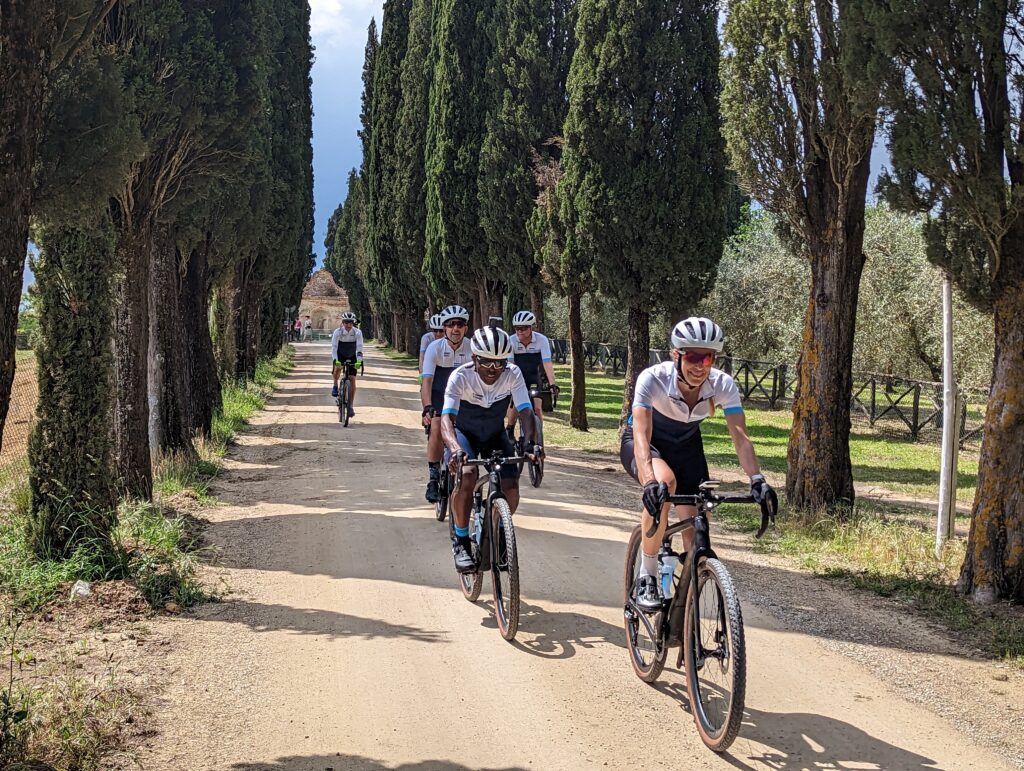 Group of cyclists riding a tree lined gravel road